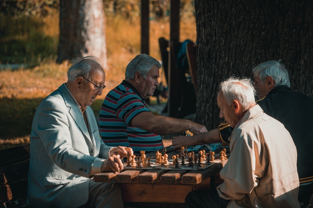 Two elderly men playing chess at a wooden table